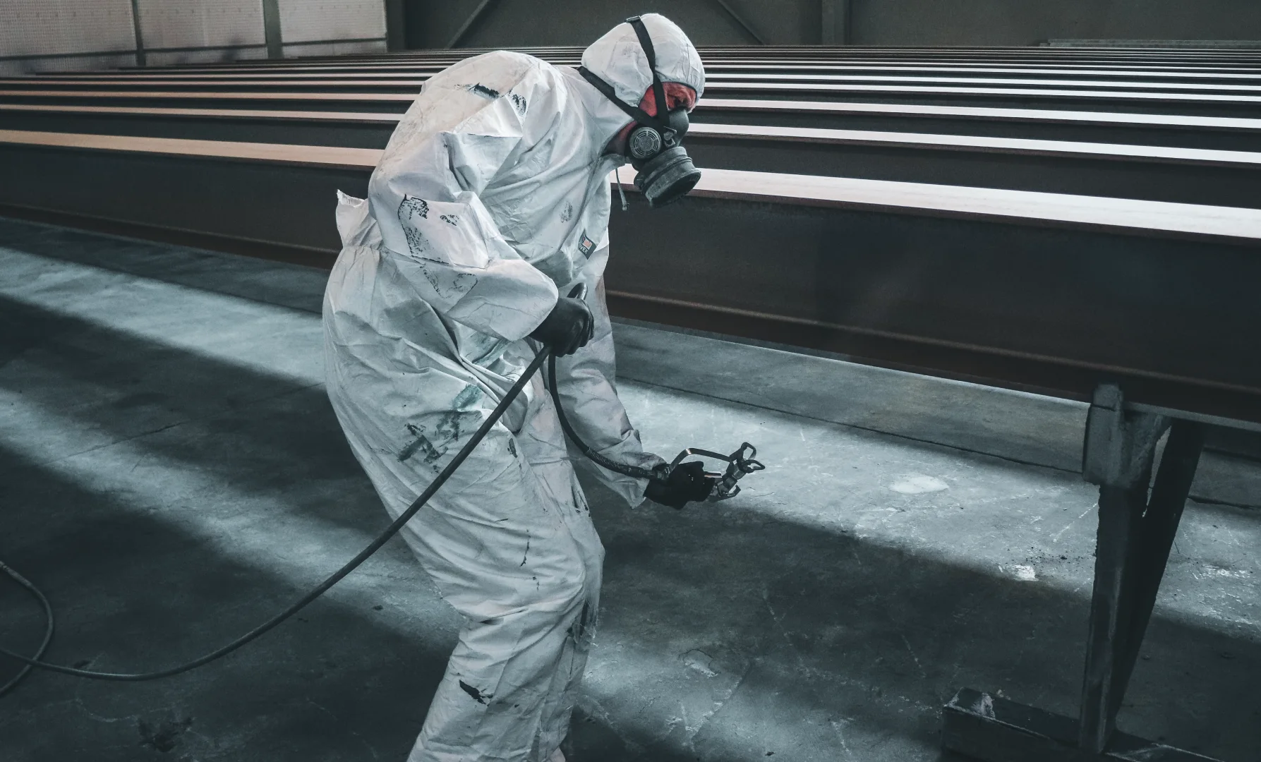 Sandblasting and painting of steel beams in a controlled industrial environment